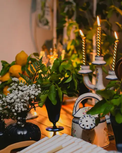 Mesa del café con velas encendidas, flores blancas y una tetera de porcelana